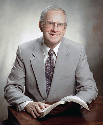Portrait of Dr. Robert Finley, smiling at the camera while holding a bible