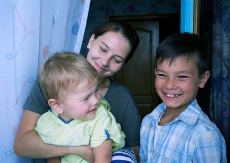 A mother with two young children under the child and missionary sponsorship program, smiling at the camera